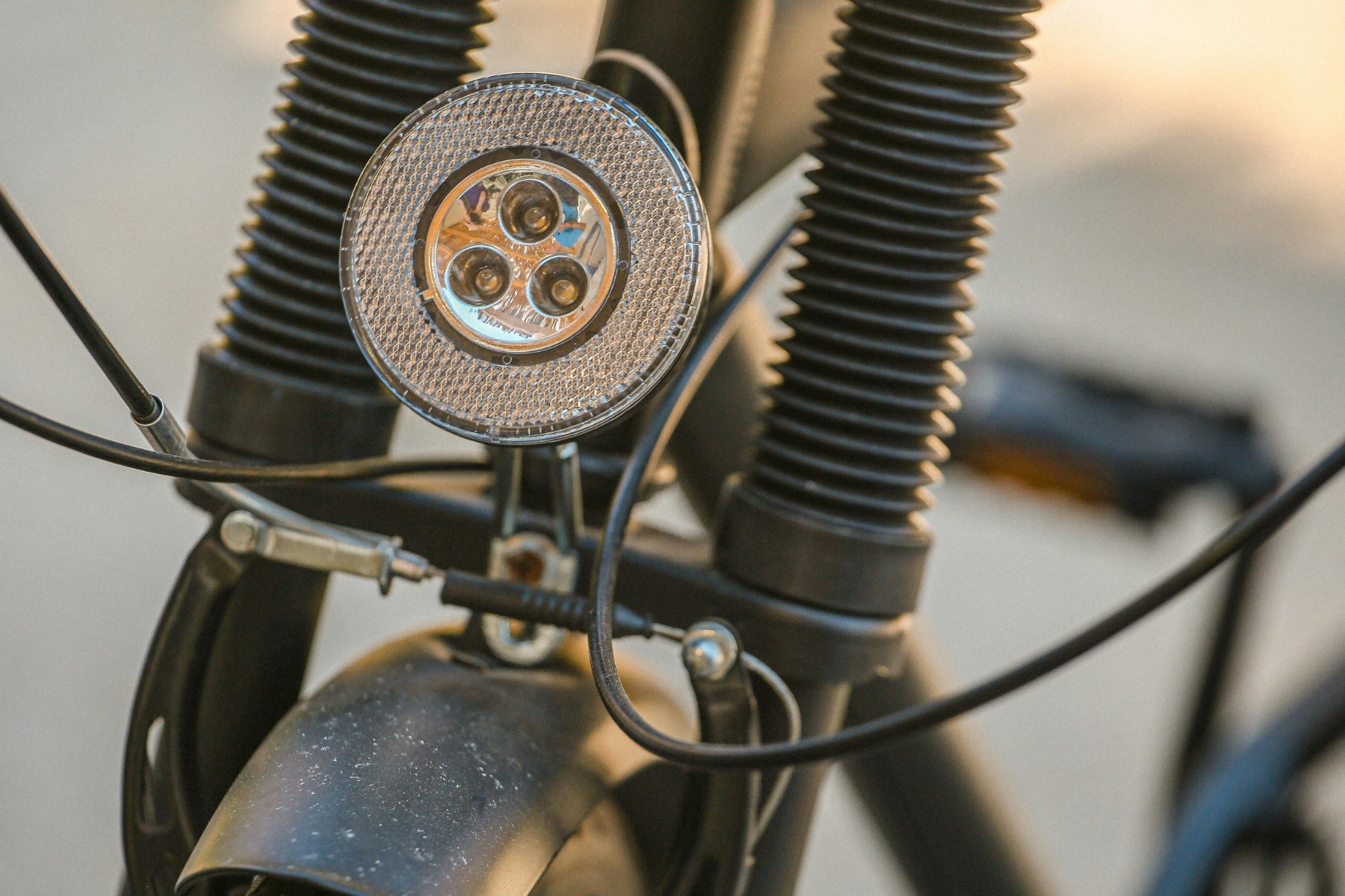 Detail view of a bicycle's headlight and shock absorber in daylight.