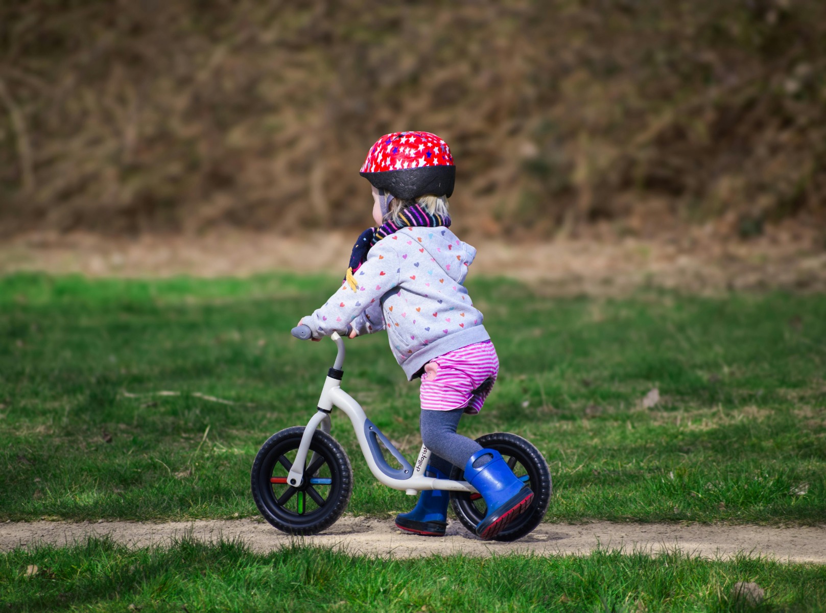 A father helps his daughter learn to ride a bike on a sunny day, fostering bonding and skill development.